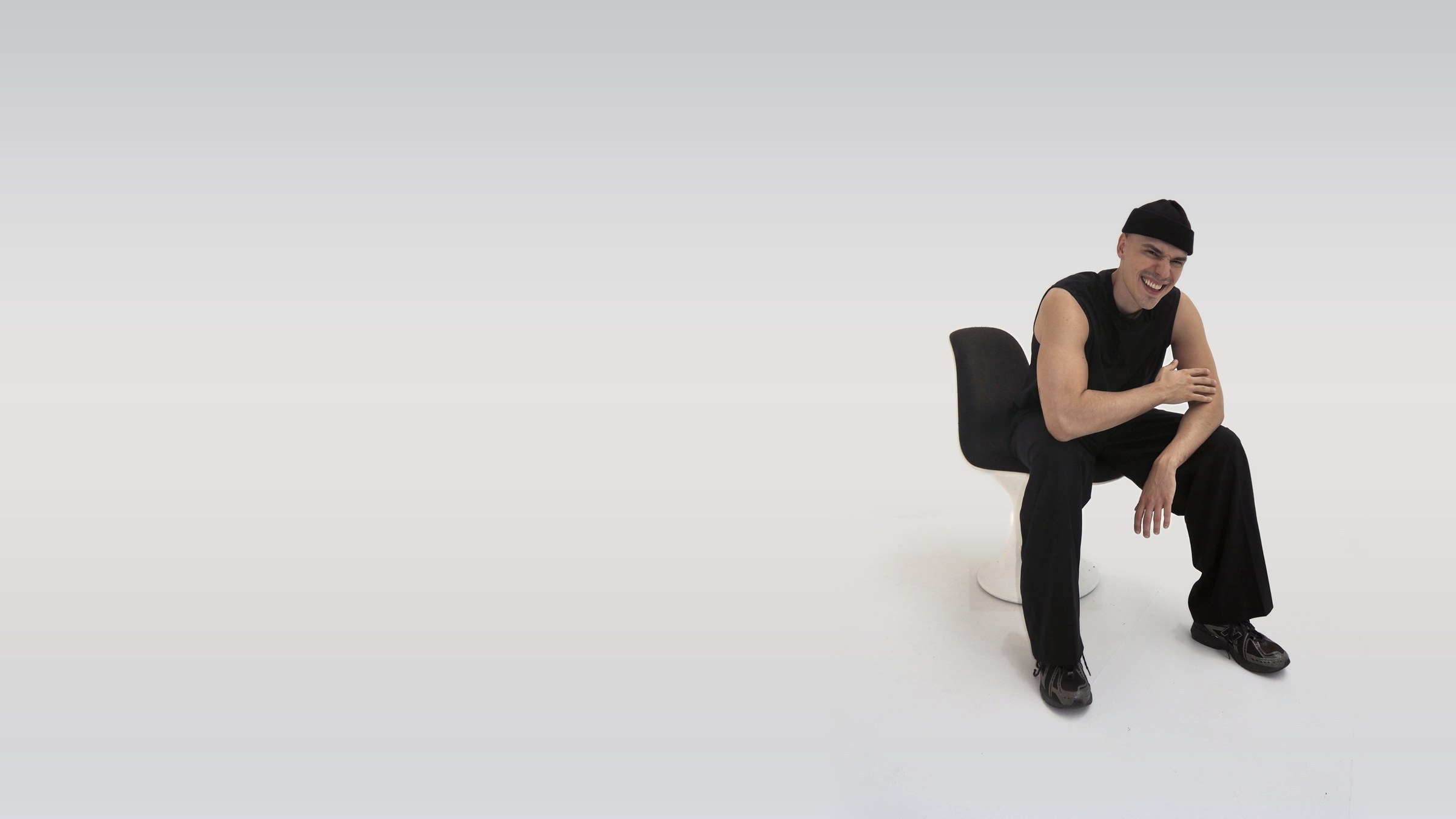 Til Streitbörger, Content Creator und Influencer aus Köln, lachend auf einem Designstuhl im hellen Studio